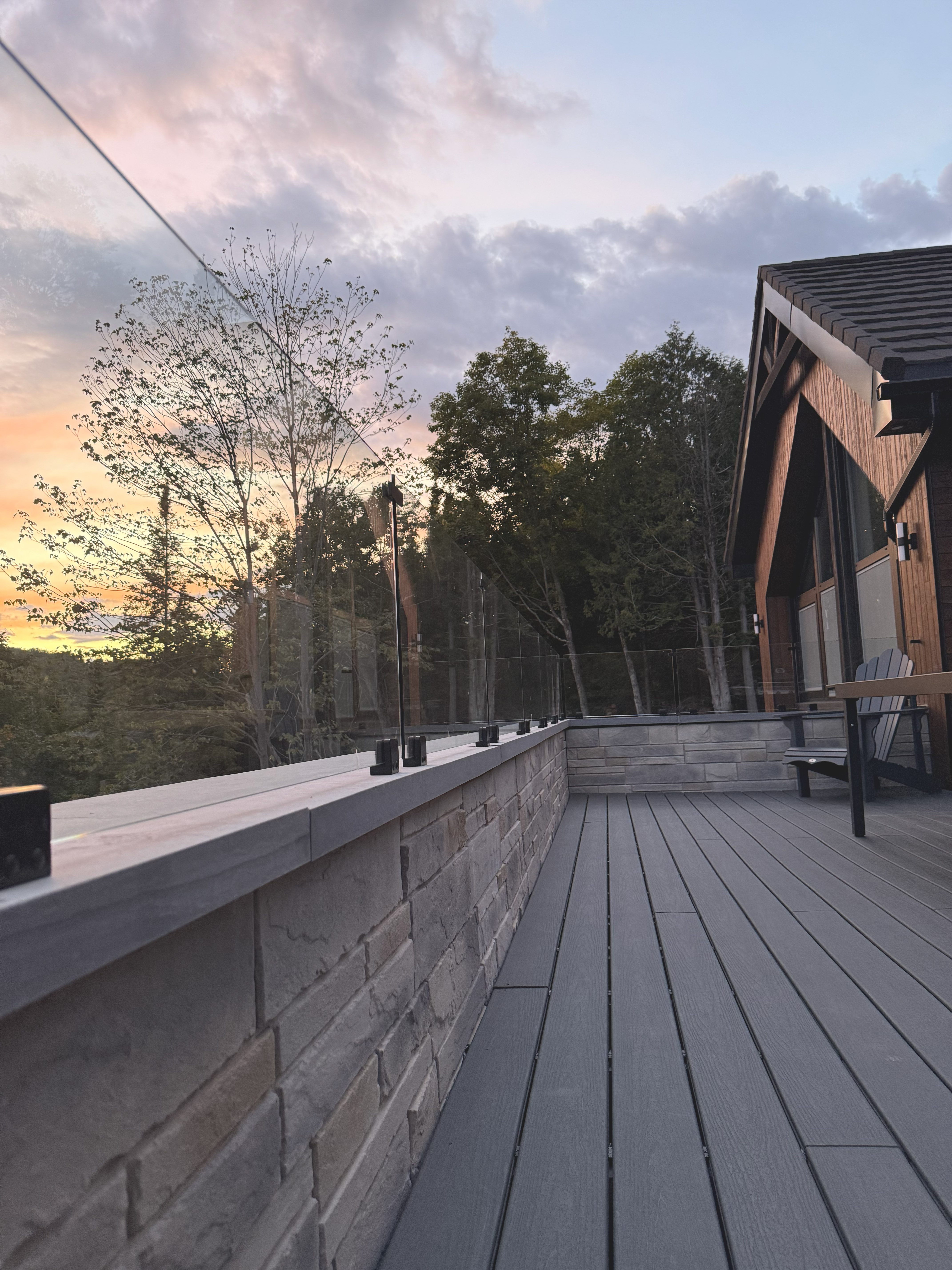 Chalet deck at sunset, glass railing and stone base